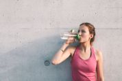 Eine junge Frau in Sportbekleidung trinkt aus einer Trinkflasche. Eine junge Frau in Sportbekleidung trinkt aus einer Trinkflasche.